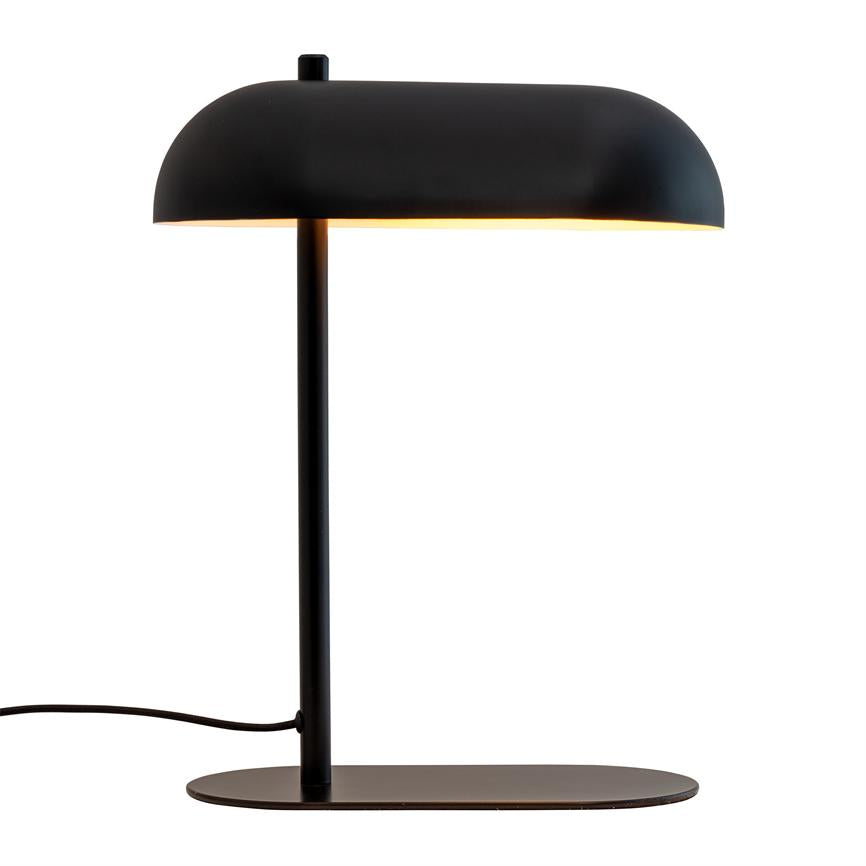 Bordlampe med sort, buet skærm, der udstråler varmt lys nedad; tynd lodret stang forbinder til flad oval metalfod, med strømkabel ud til venstre på hvid baggrund.