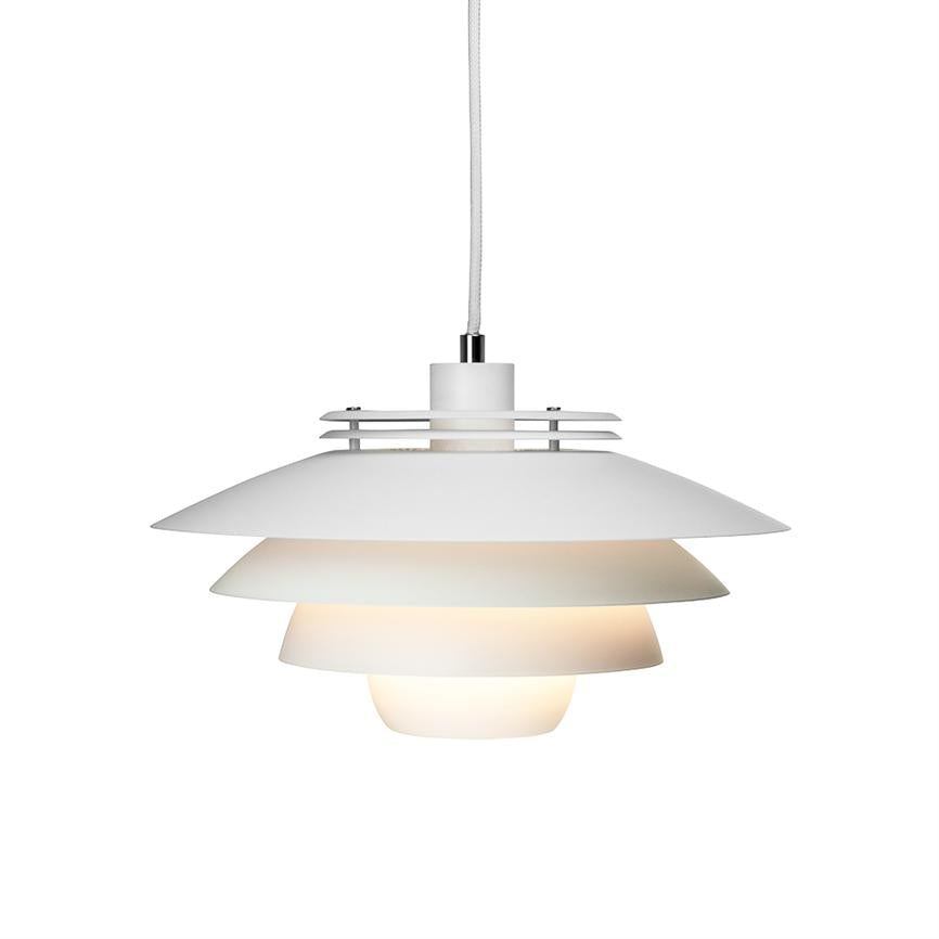 En hvid, lagdelt pendel-lampe udsender blødt, varmt lys og hænger i en tekstilbeklædt ledning foran en neutral, hvid baggrund.