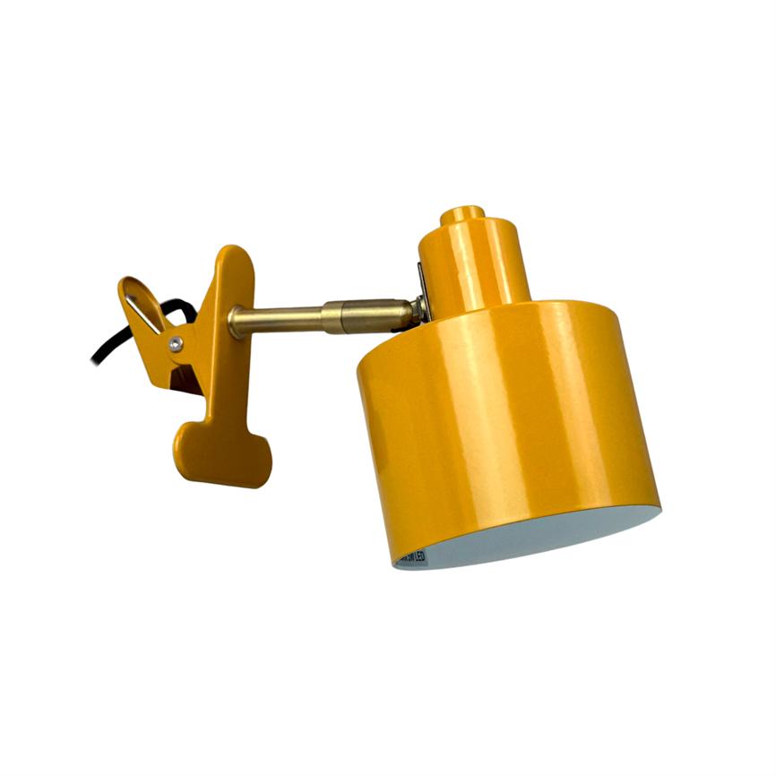 En gul clip-lampe klemmer fast på en justerbar metalarm og peger nedad; armens leddelte beslag og sorte kabel er synlige mod en ensartet hvid baggrund.